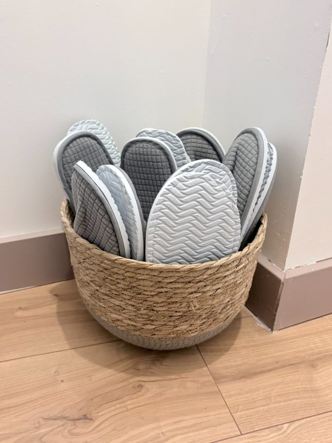 Bac en osier contenant des sandales grises empilées verticalement.