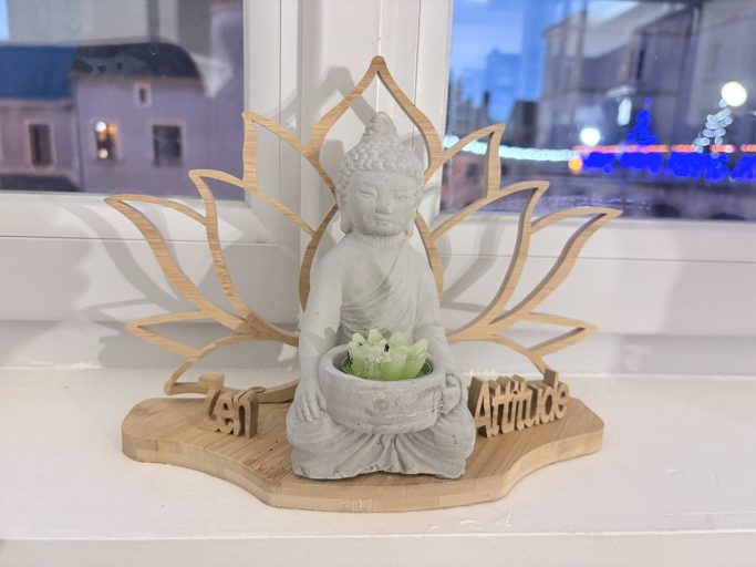 Statue de Bouddha sur un socle en bois, entourée de fleurs de lotus.